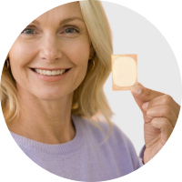 A close-up of a middle-aged woman holding up a patch.