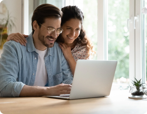 Man and woman smiling while using a laptop together