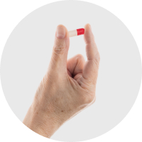 A hand on a white background holding a capsule.