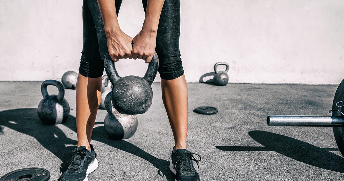 Close up of young woman lifting kettlebell.