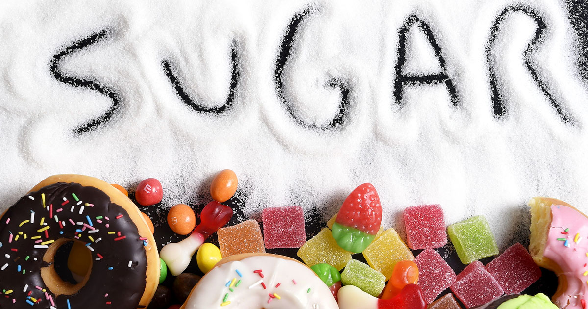 “Sugar” spelt out in a pile of sugar surrounded by sweet foods.