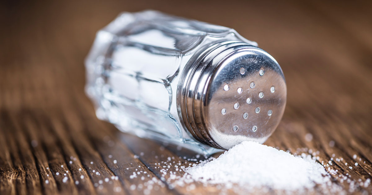 Salt shaker spilling out onto table.