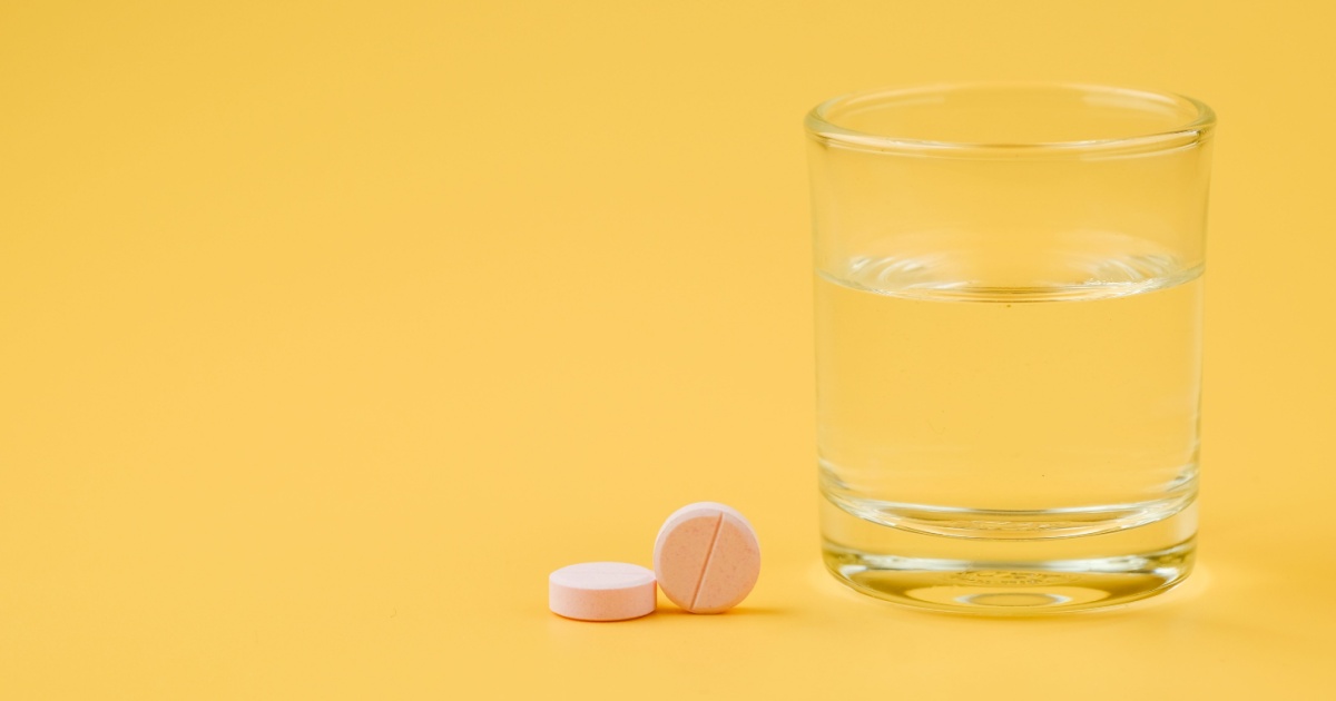 Image of water and pills against a yellow background