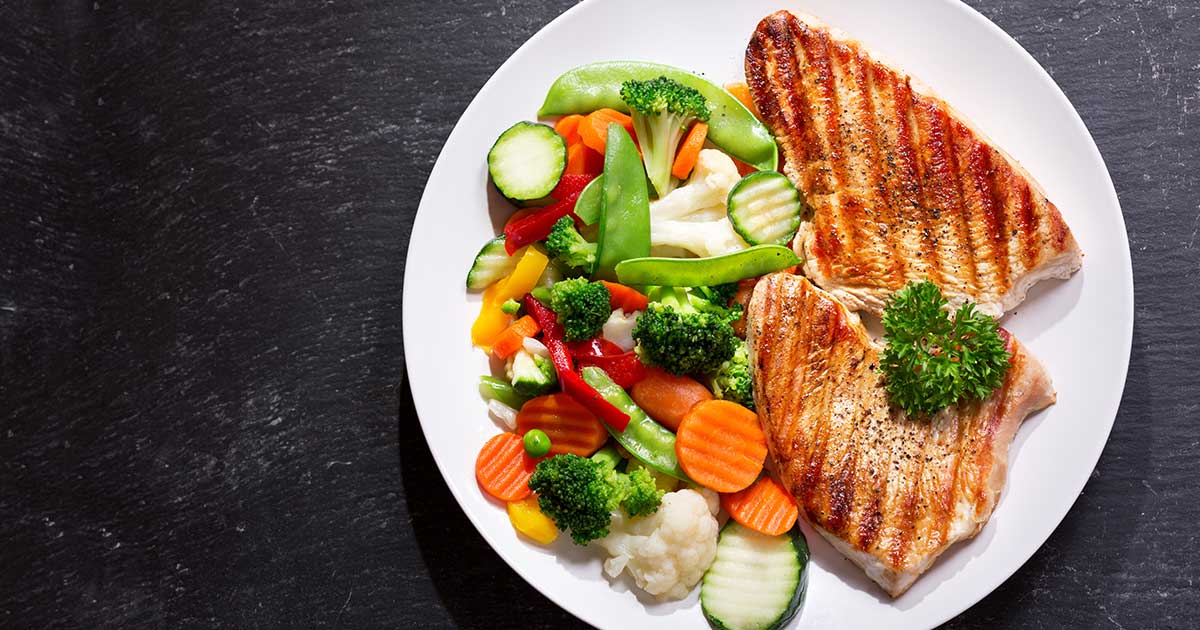 A plate of grilled chicken with a side of steamed vegetables.