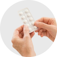 A close-up of a woman holding a pack of pills.