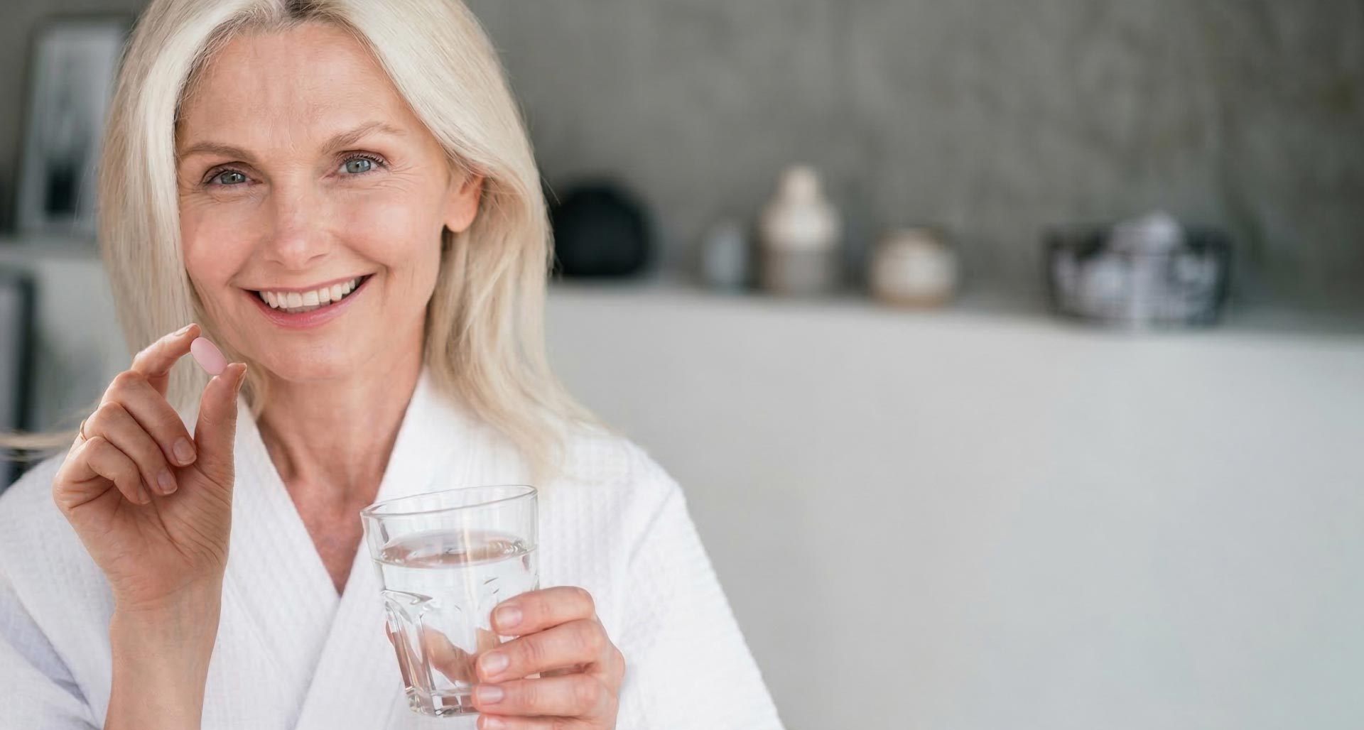  A mature woman taking a pink capsule with a glass of water